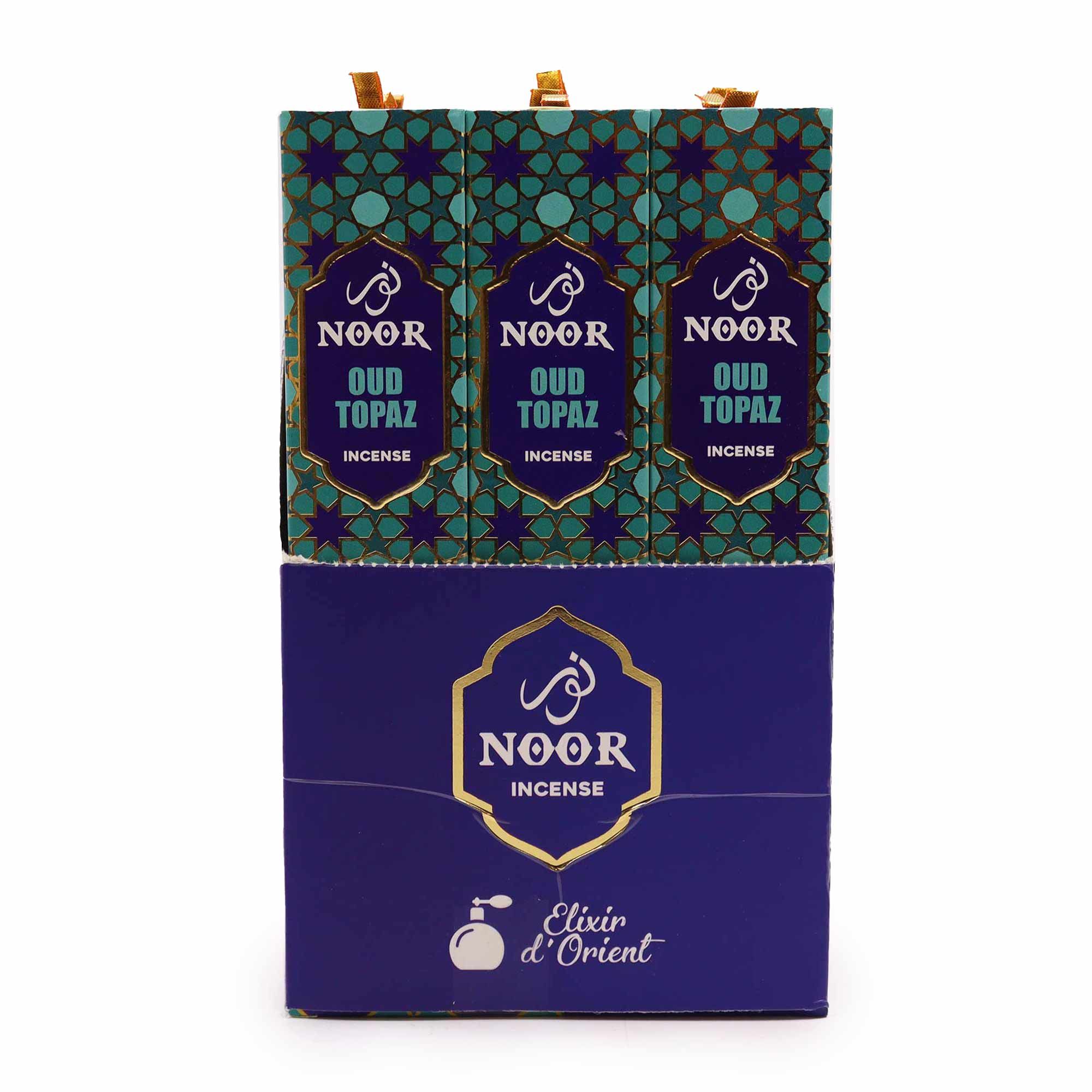 Embalaje del incienso Noor Oud Topaz en tonos turquesa y azul con detalles dorados.